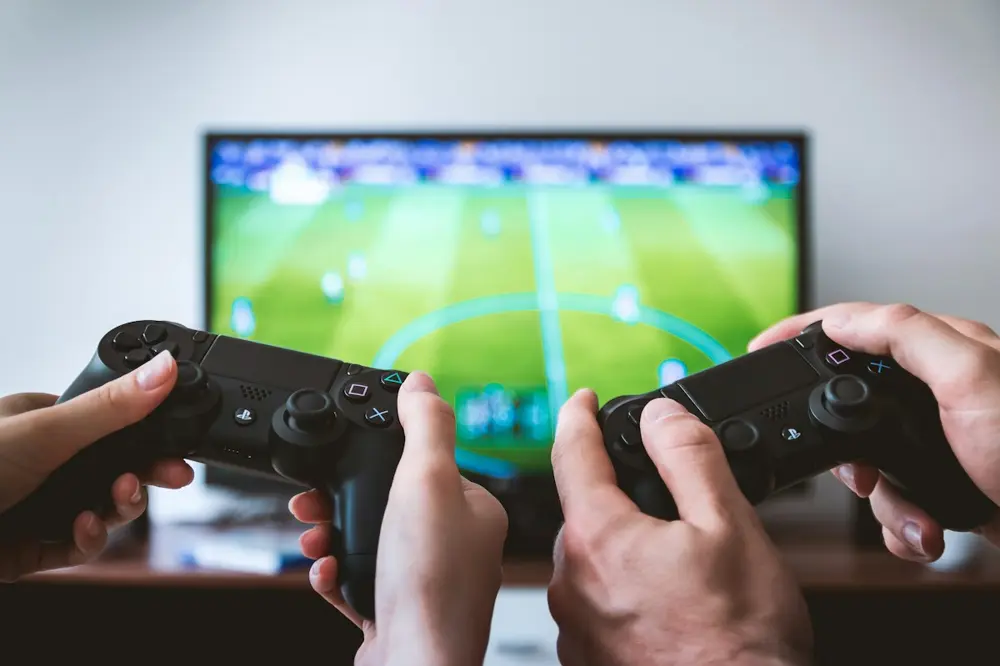 Two players holding DualShock 4 controllers during a football game